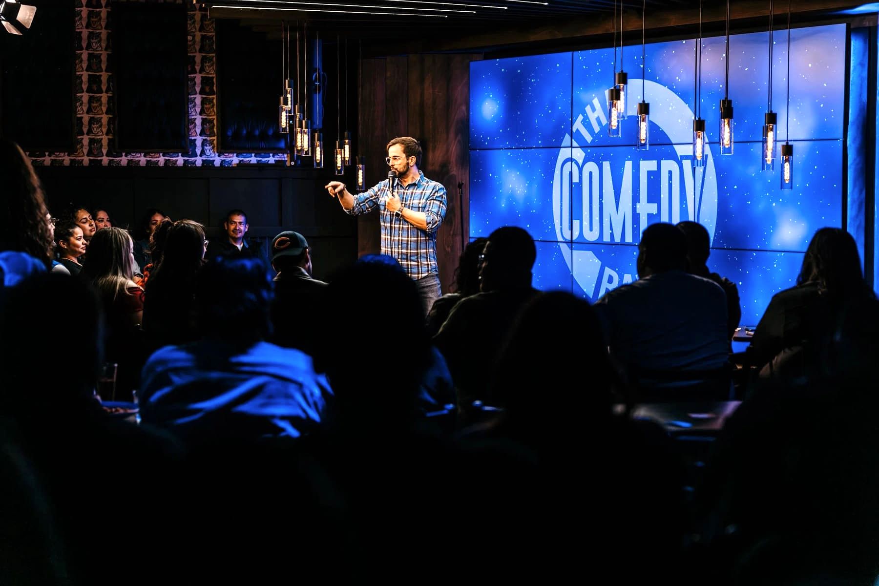 A comedian performing on stage at The Comedy Bar