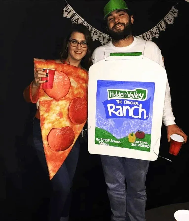 Two people in Halloween costumes, one dressed as a pizza slice and the other as a ranch dressing bottle holding drinks