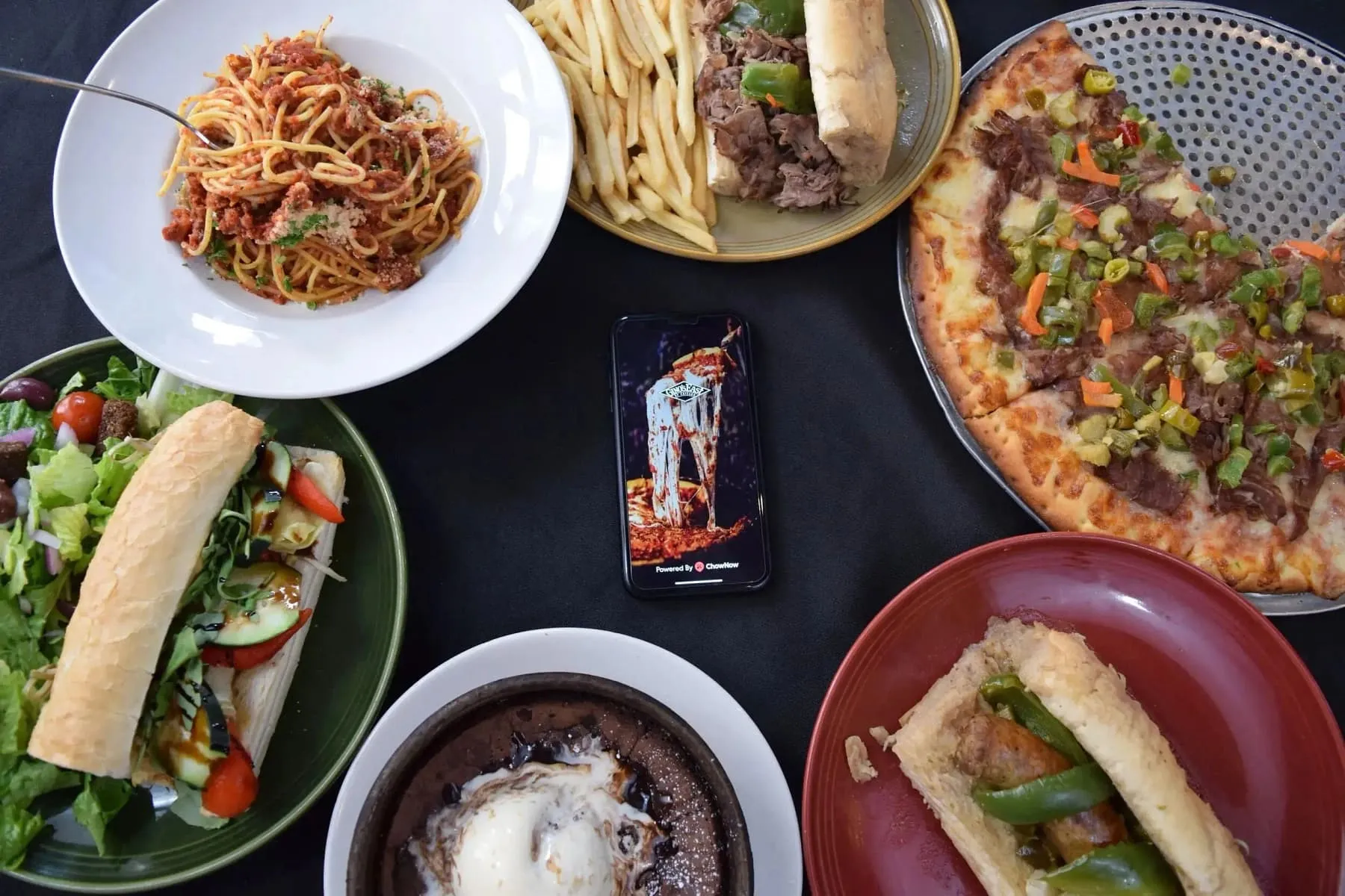 Overhead view of a table spread with pasta and pizza alongside sandwiches and salad