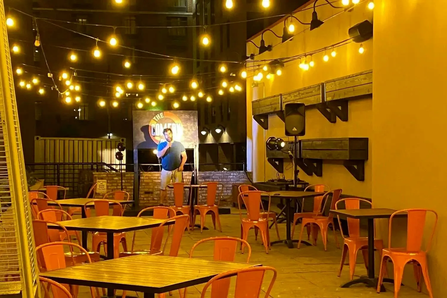 Outdoor patio dining with string lights and orange chairs at Gino's East