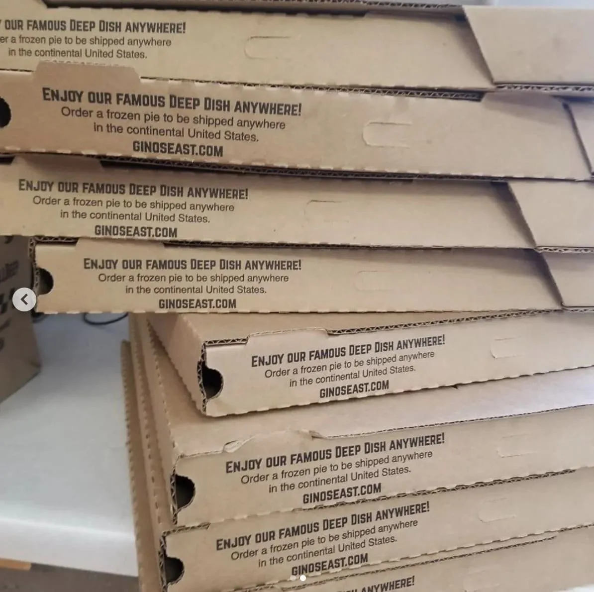 Stack of Gino’s East pizza boxes printed with an ad for shipping frozen deep dish nationwide