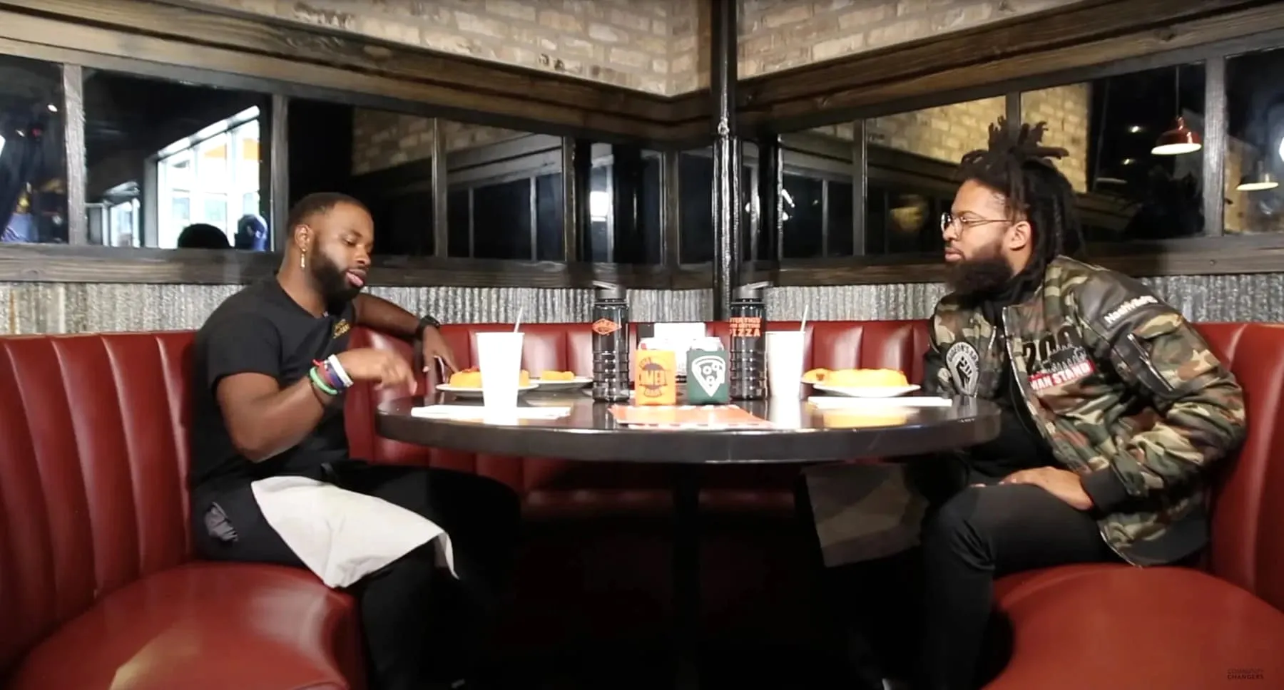 Jerome Moore and Jamel Campbell-Gooch of Gideon's Army seated in a Gino's East booth with pizza
