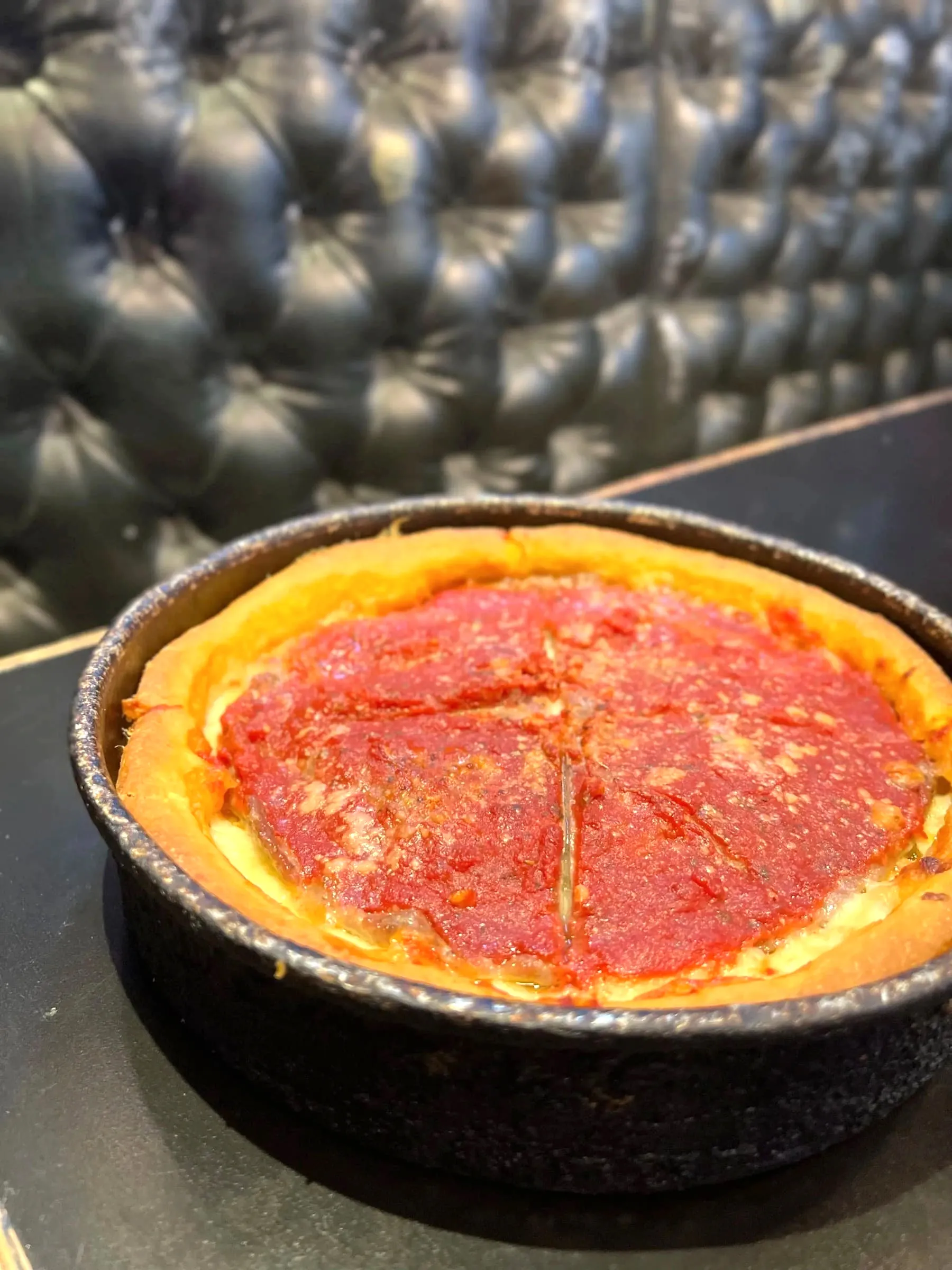 A whole deep dish pizza in its pan, freshly cut into quarters