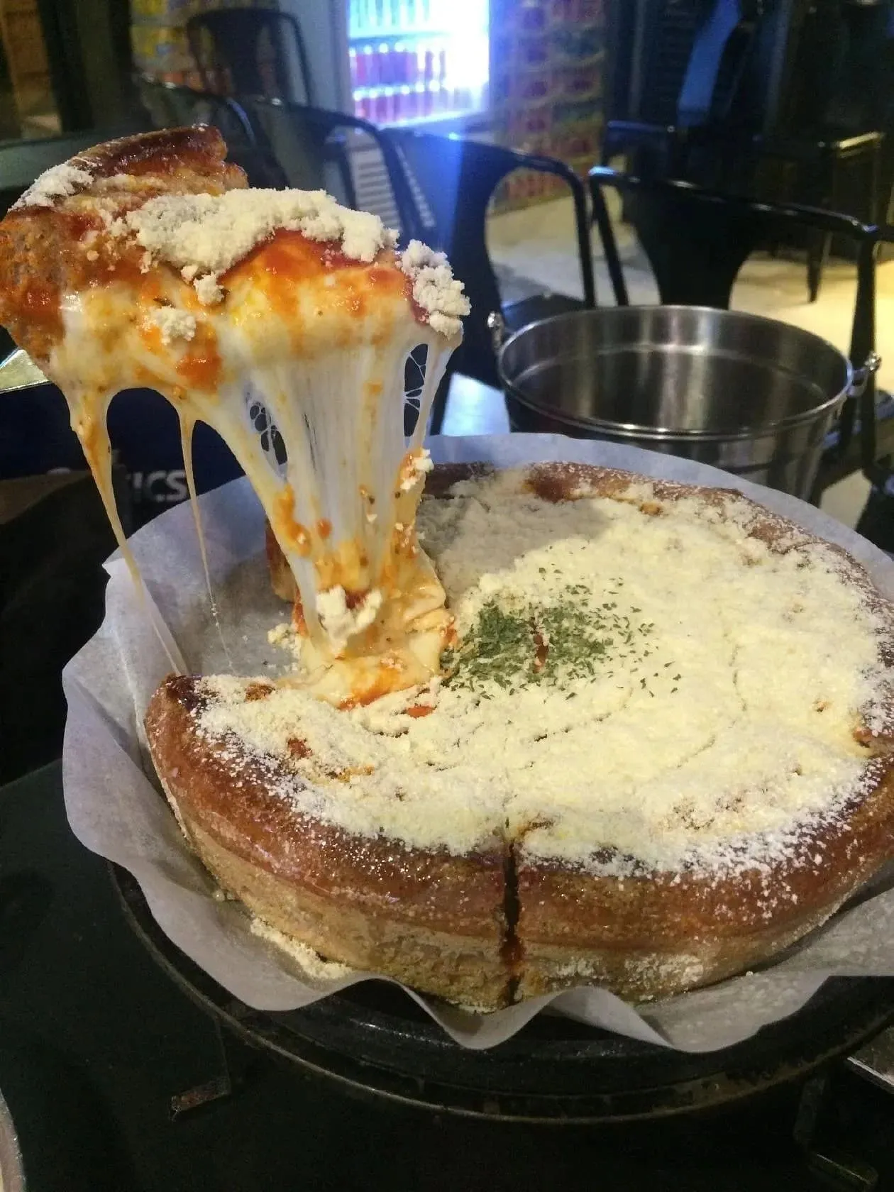A deep dish pizza with a stretchy cheese pull and parmesan crust at James Chicago Pizza in Seoul