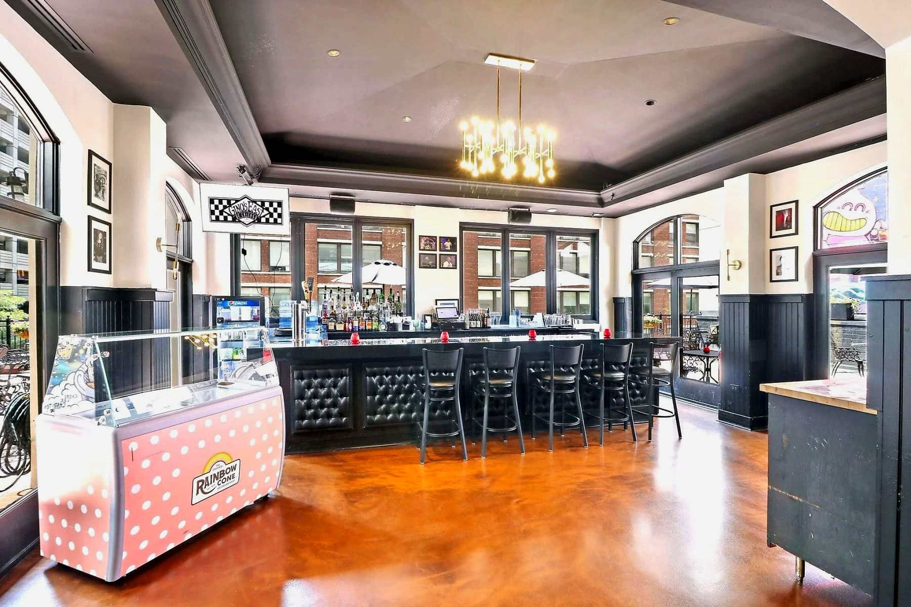 Bar area at Gino's East Magnificent Mile with barstools, a full liquor display, and a Rainbow Cone ice cream freezer
