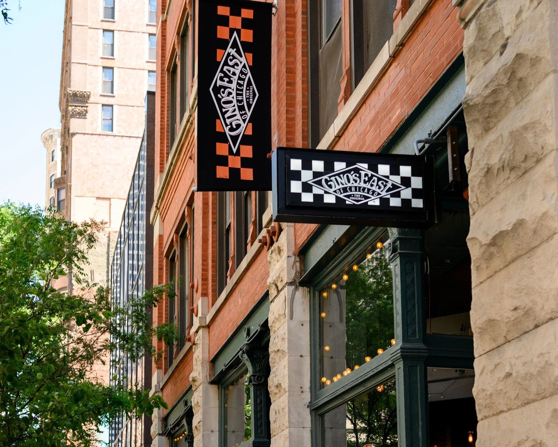 Exterior signage at Gino's East South Loop, with Gino's East of Chicago diamond-logo banners on the building corner