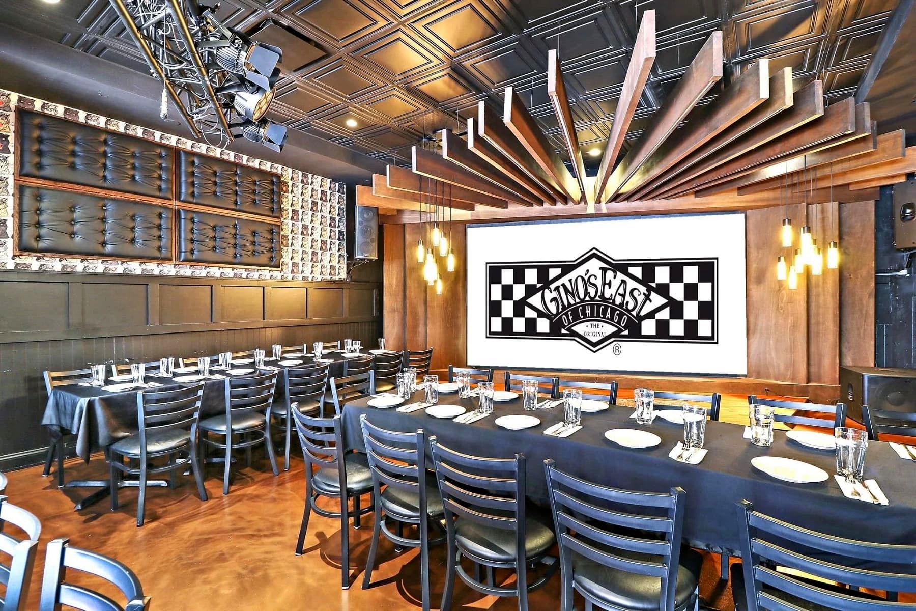 Private event room at Gino's East Magnificent Mile set up with long banquet tables facing a stage