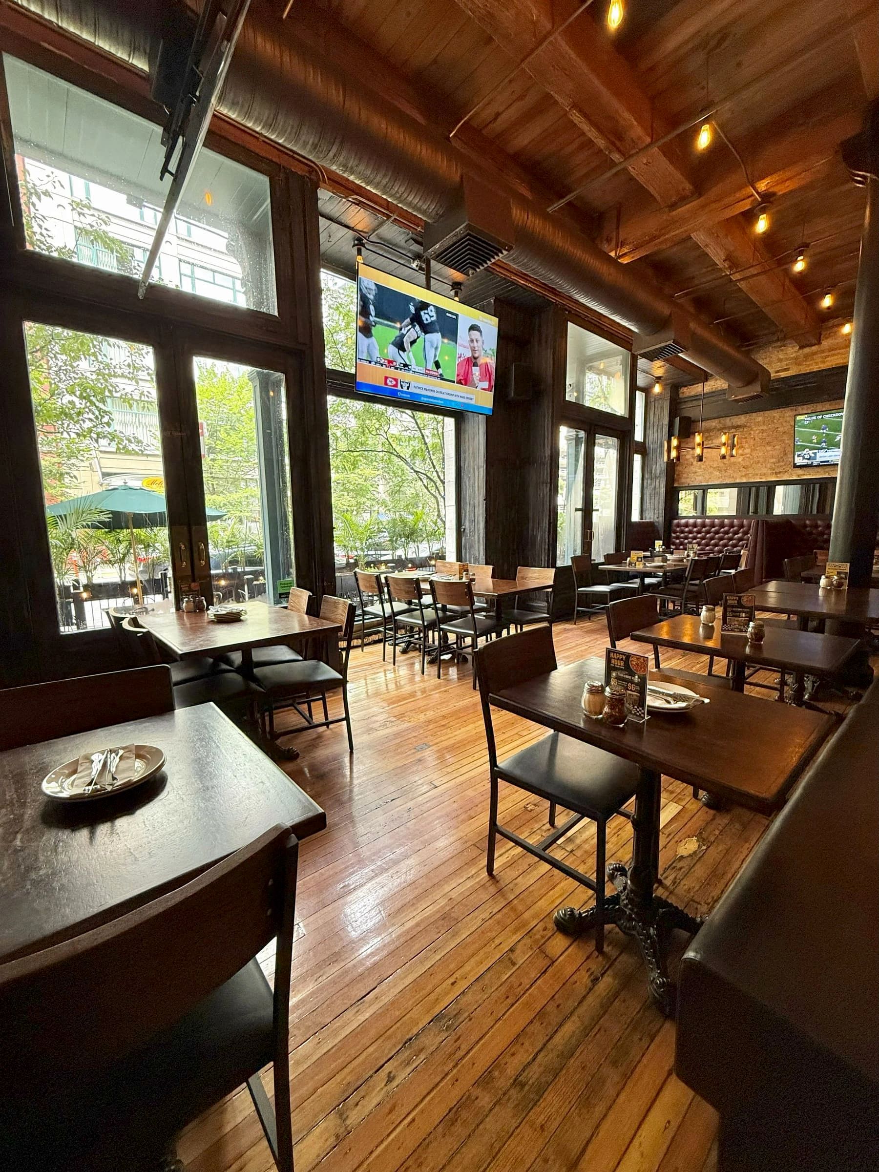Dining room at Gino's East South Loop with a wood-beam ceiling, pendant lighting, and a wall-mounted TV, tables set and empty