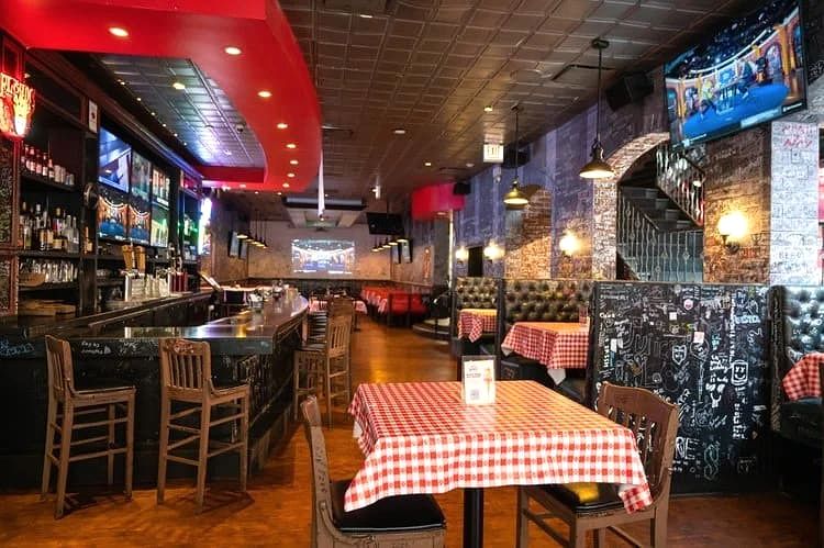 Bar and red-checkered tables beside graffiti-covered booths at Gino's East Magnificent Mile