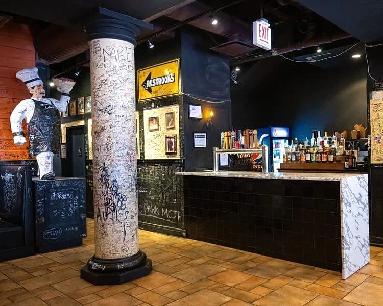 Chef statue and signature-covered column beside the bar at Gino's East Magnificent Mile