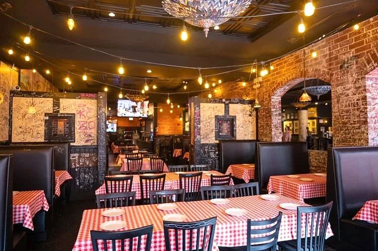 Dining room with string lights, red-checkered tables, and graffiti walls at Gino's East Magnificent Mile