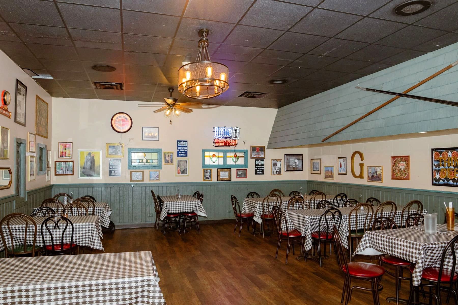 Dining room at Gino's East Wheaton with checkerboard tablecloths, vintage photos, and neon beer signage on the walls