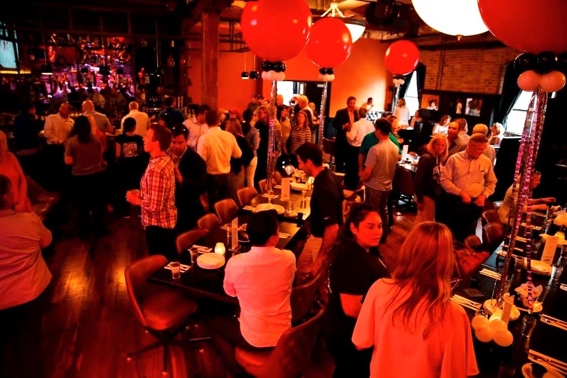 People gathered in a lively, dimly lit room at a Gino’s East event