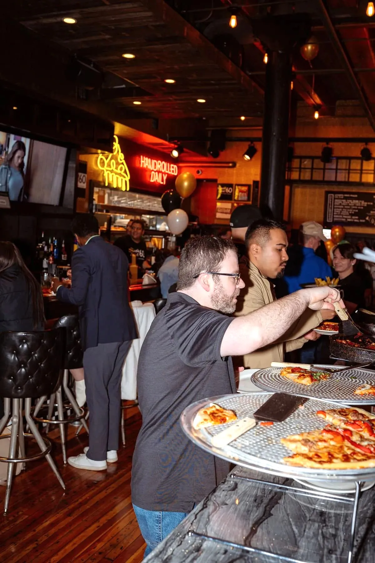 A staff member serving pizza slices to guests during the Gino’s East South Loop reopening event