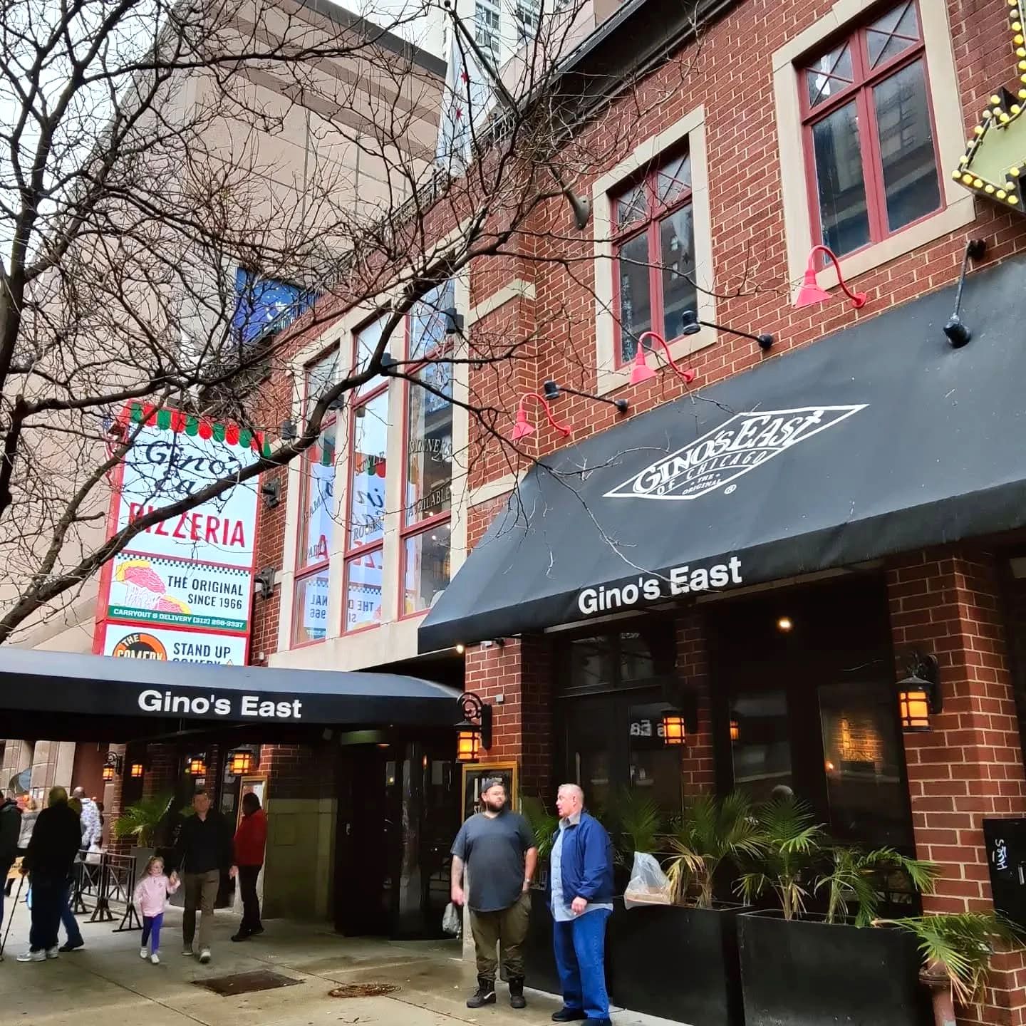 Brick exterior of Gino's East Magnificent Mile on Superior Street, with black Gino's East awnings and the vintage Pizzeria sign