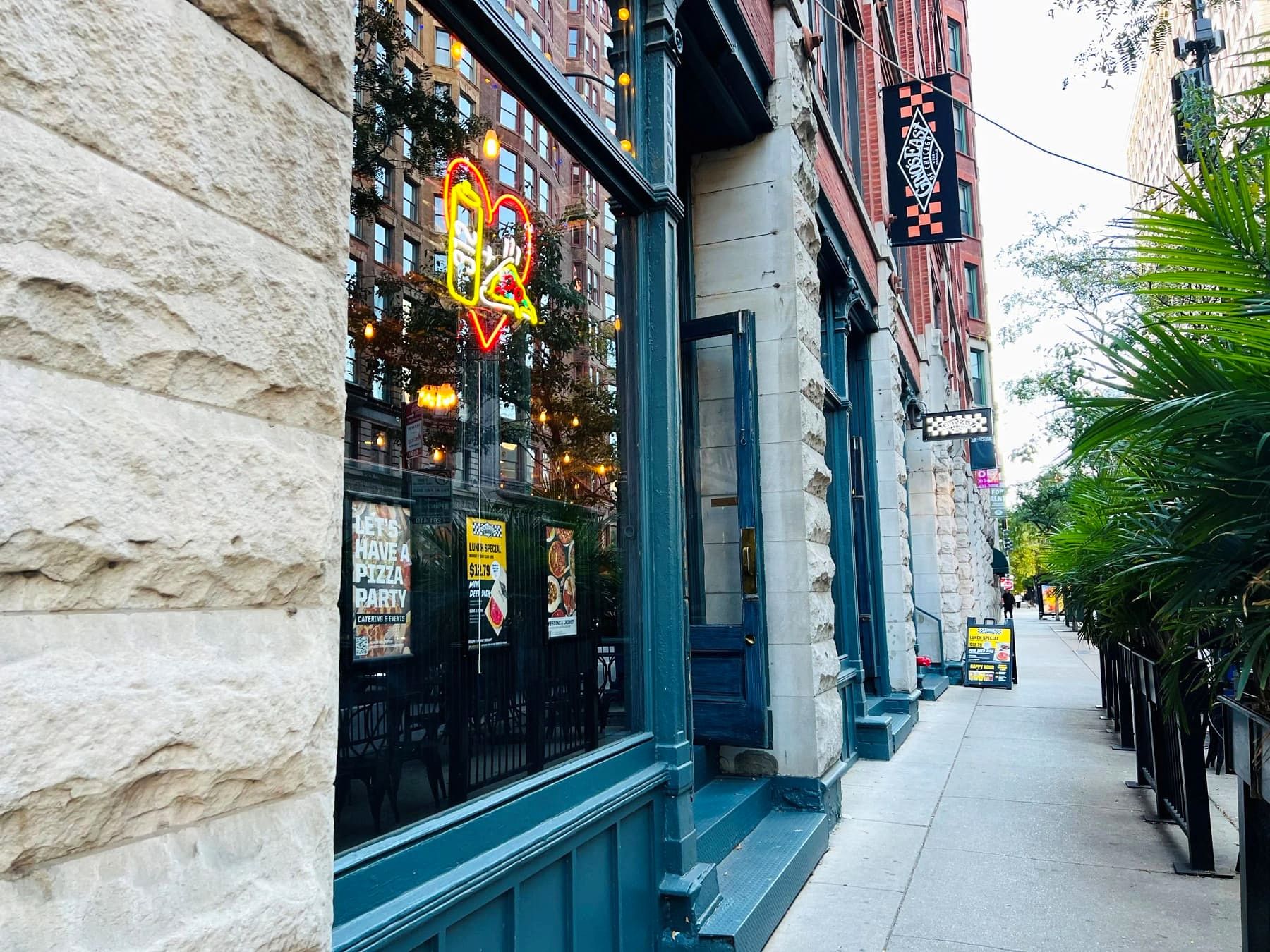 Sidewalk outside Gino's East South Loop, with the restaurant's neon sign glowing in the window and the street stretching into the distance