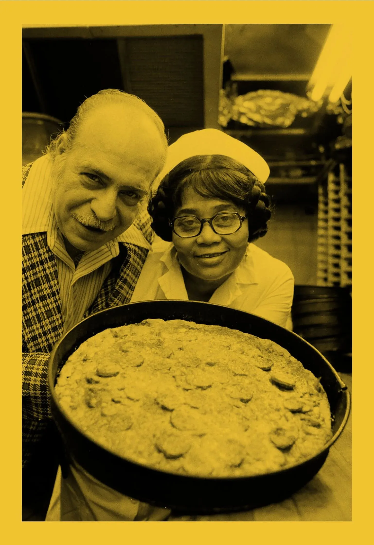 Vintage photo of Fred Bartoli and Alice Mae Redmond in a cap and glasses, smiling behind a deep dish pizza in its pan