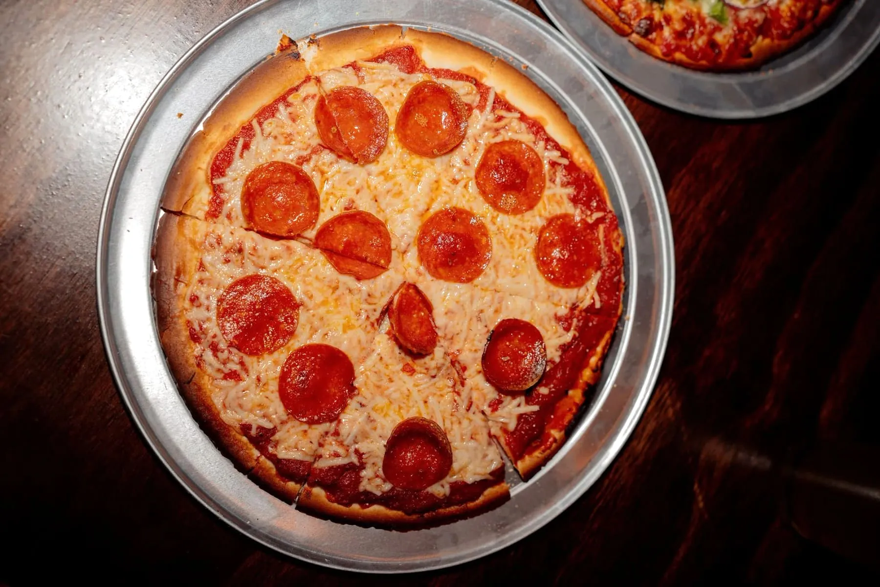 A gluten-free pepperoni pizza with melted cheese on a round metal pizza pan