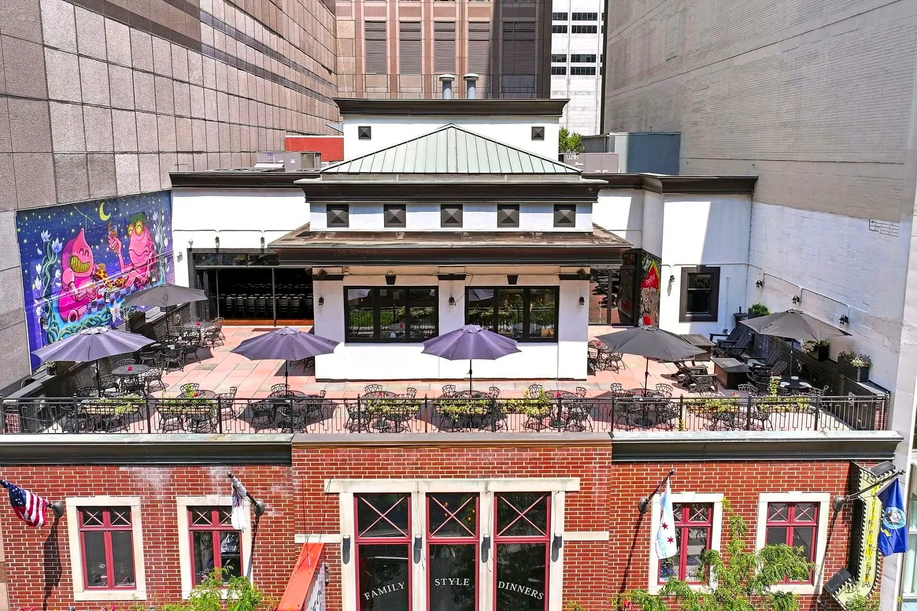Rooftop terrace at Gino’s East Magnificent Mile seen from above, with purple umbrellas, iron tables and a colorful mural on the neighboring wall