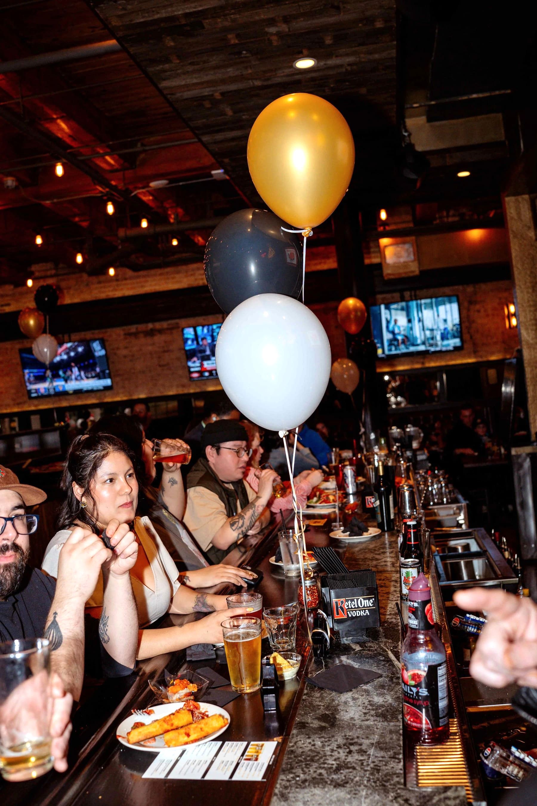 Guests celebrating with balloons at the bar during an event at Gino's East South Loop